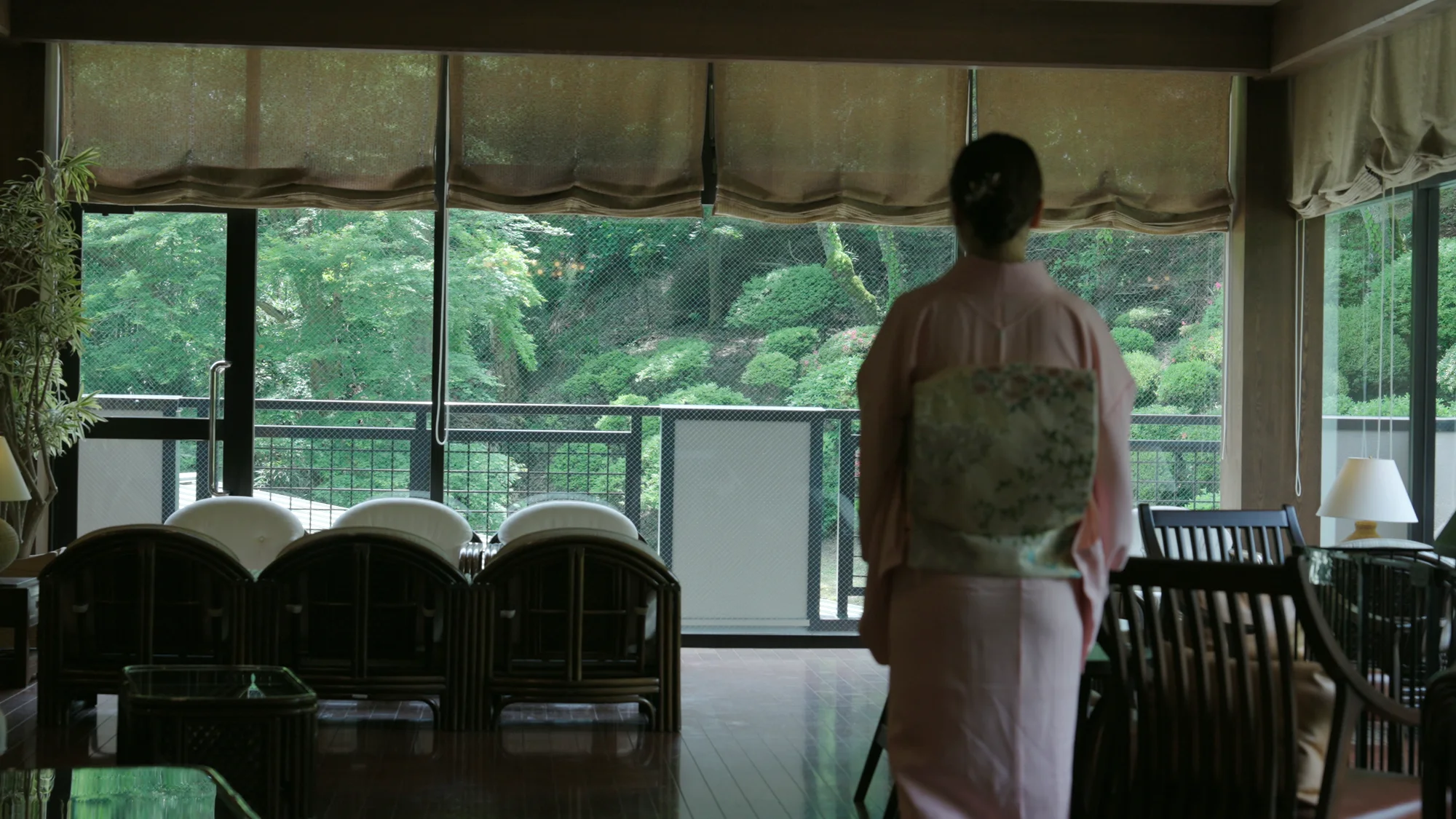 宿のラウンジの窓辺に立つ、着物の人の後ろ姿